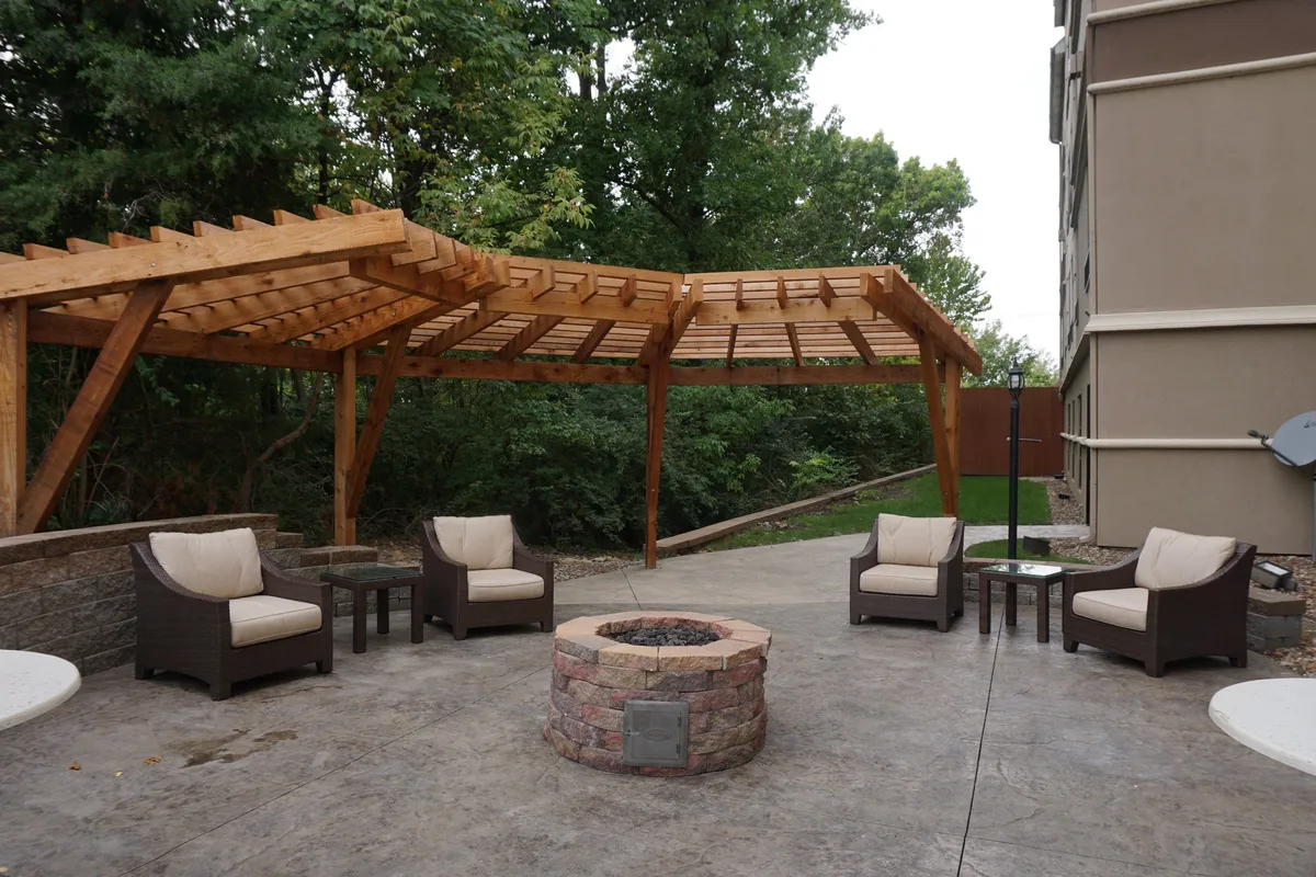 This exterior space features a wooden pergola, cozy fire pit, and comfortable lounge seating. The setting is ideal for relaxation and social gatherings, fostering warm evenings and shared moments with loved ones.