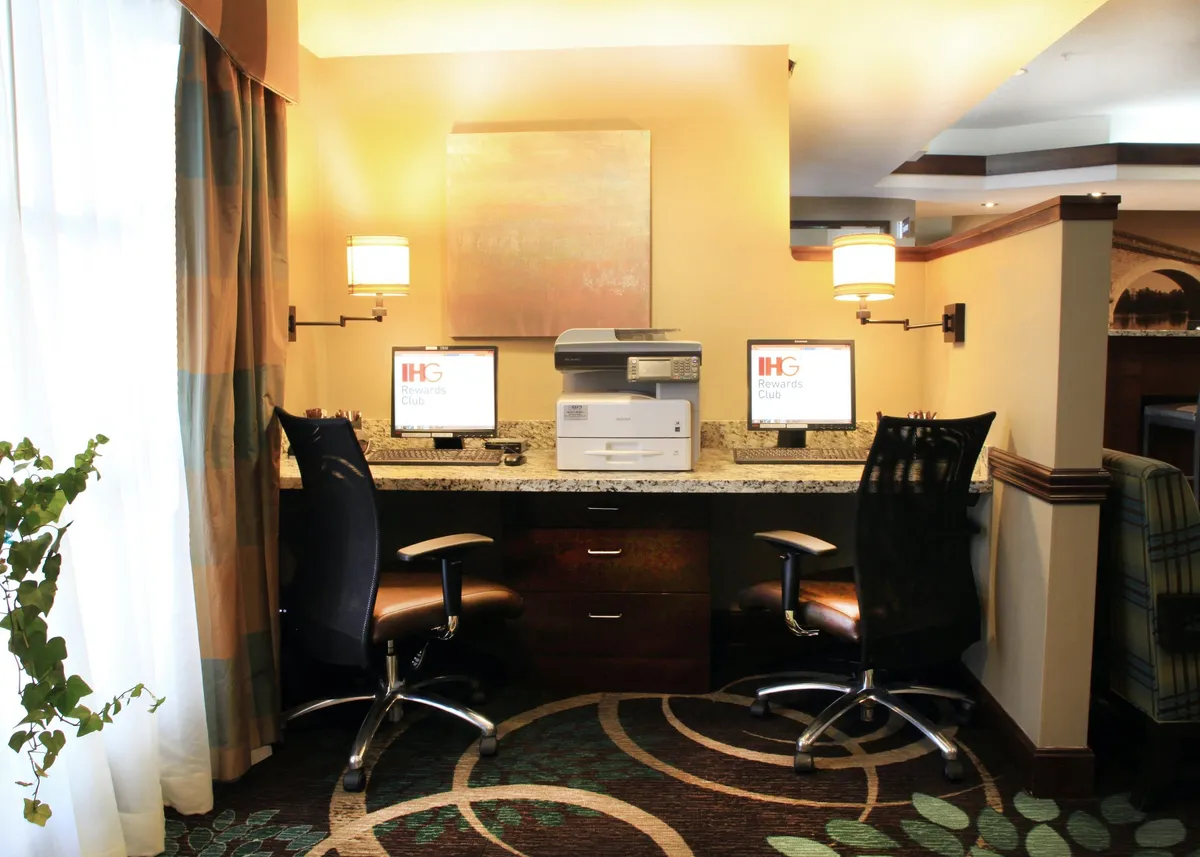 A compact workspace with two computer workstations, a printer, and tastefully arranged decor, designed for productivity and focus. Soft lighting and thoughtful layout provide a conducive environment for both work and relaxation.