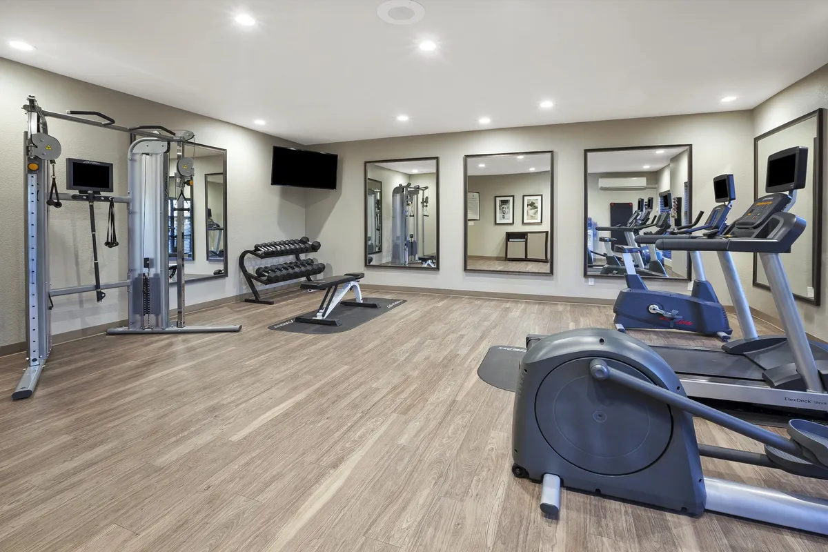 A bright, well-equipped fitness center featuring various exercise machines, free weights, and mirrors. The space feels energetic and motivating, providing ample room for solo or group workouts.