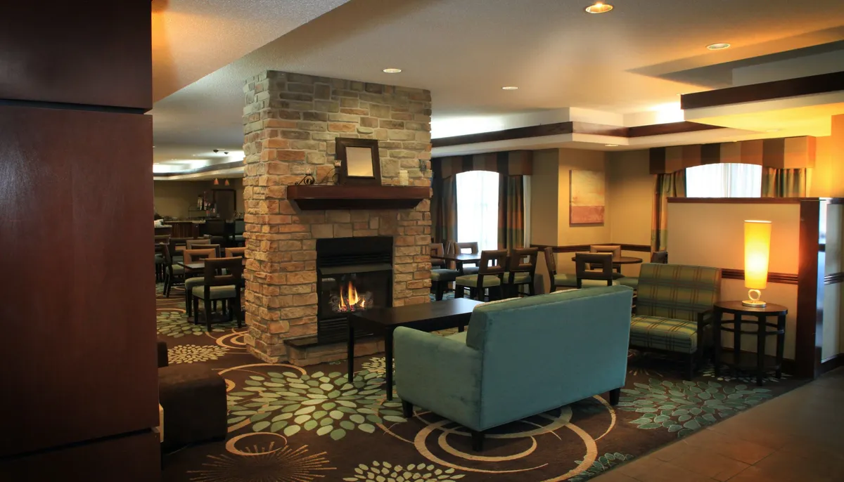 A welcoming interior featuring a cozy fireplace, plush seating area, and a decorative rug, creating a comfortable setting for relaxation and socializing. The arrangement invites guests to unwind, read, or connect with friends, evoking the feel of a homey retreat.